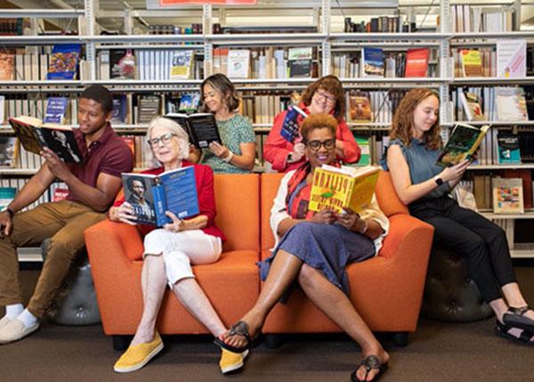 People sitting in the library reading a variety of different books